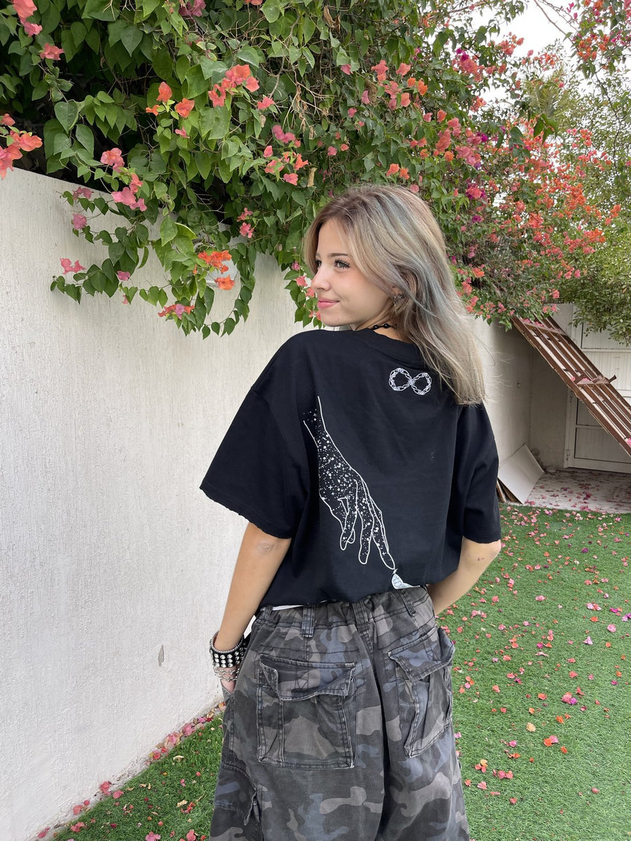 Model wearing the black Past x Future tee, back print, under bougainvillea